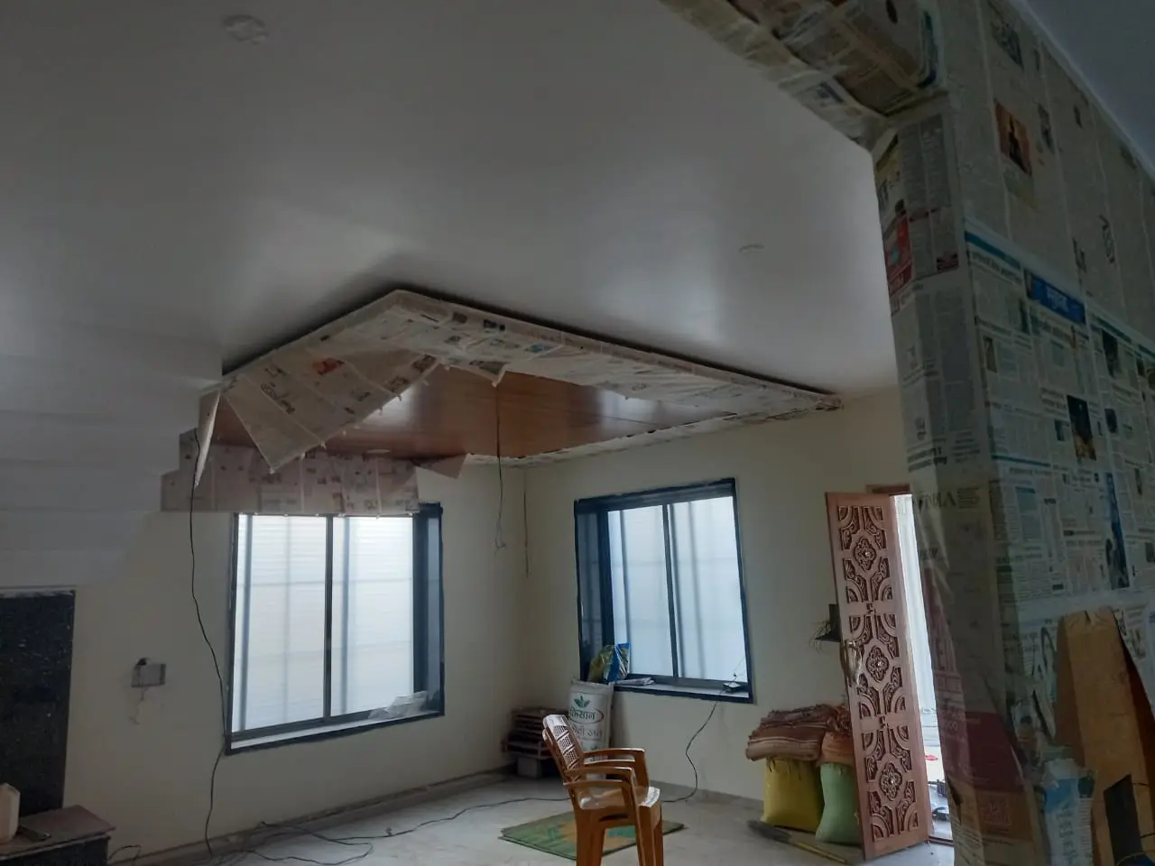 a room with a chair and a wall covered in newspaper showing pune interior design work