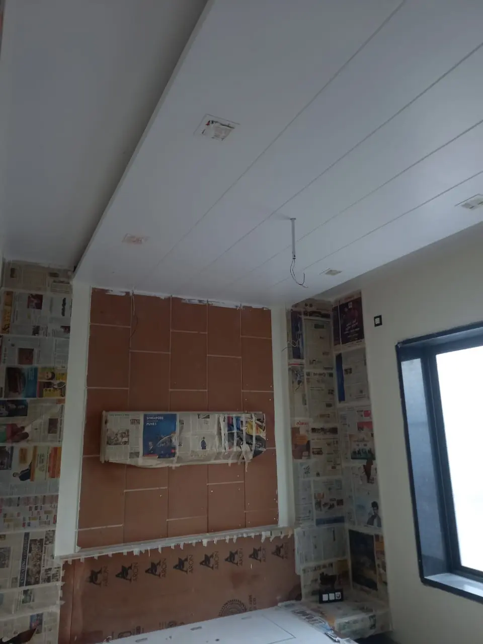 a room with a wall covered in newspaper showing pune interior design work