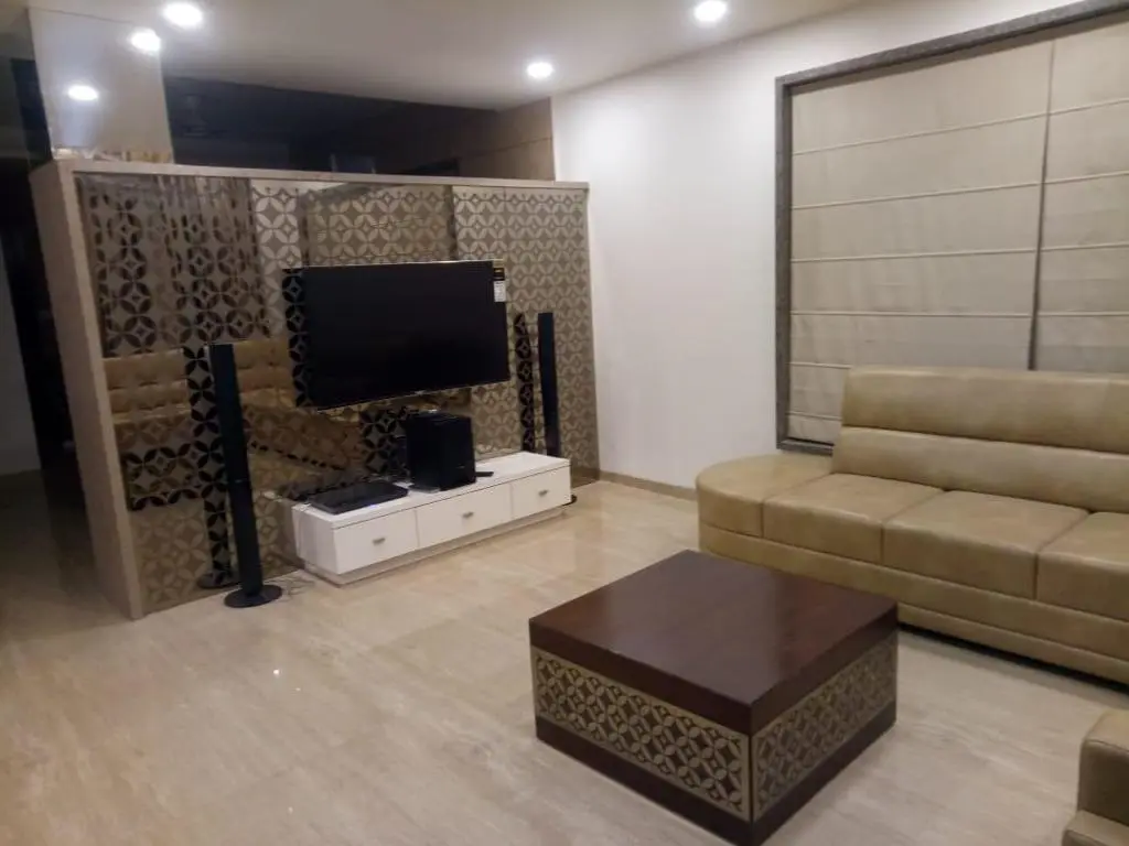 a living room with a tv and skin clour sofa showing best interior design pune