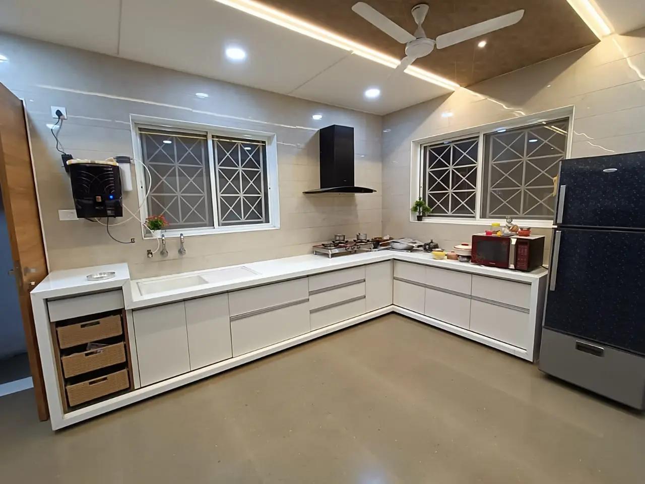 a kitchen with white cabinets and a refrigerator showing best interior design pune