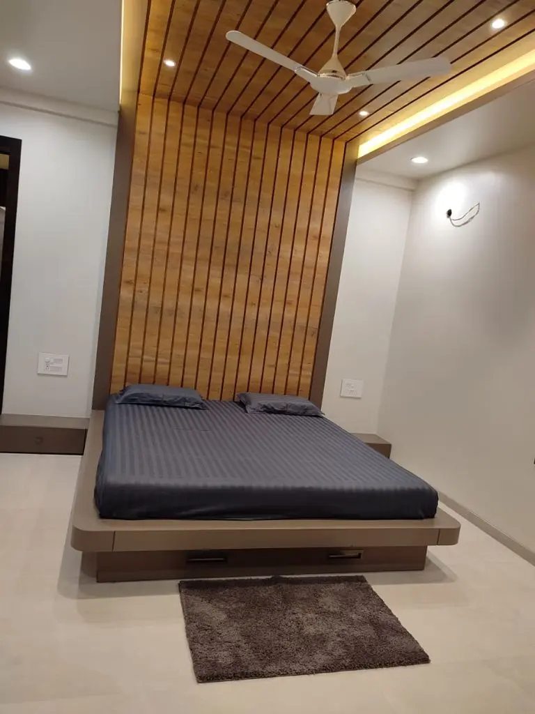 a bed with a wood paneled wall showing pune interior design